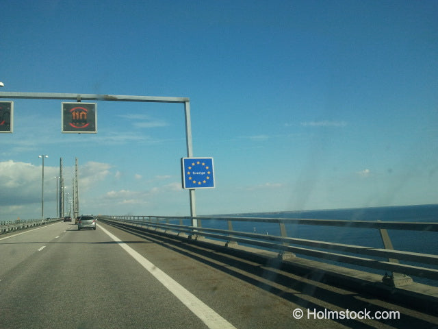 Hier rijden we over de Öresundbrug langs het bordje 'Sverige' en passeren daarmee de landsgrens naar Zweden. In de verte zie je de kustlijn van Zweden en aldaar ligt ook Malmö als meest zuidelijke stad van Zweden.