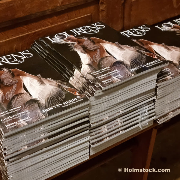 Een stapel magazines van Lourens Magazine. Een glossy magazine met focus op cultuur, kunst, architectuur en interieur, reizen en het goede leven. Holmstock Travel adverteert in Lourens Magazine met het onderwerp Noorderlichtreizen naar Finland, Zweden en Noorwegen.